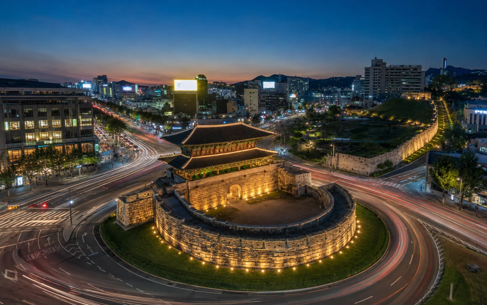 A city gate encircled by traffic at night